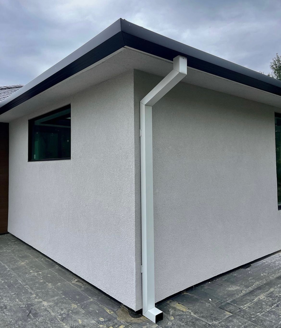 Black gutter with white downspout on a modern home